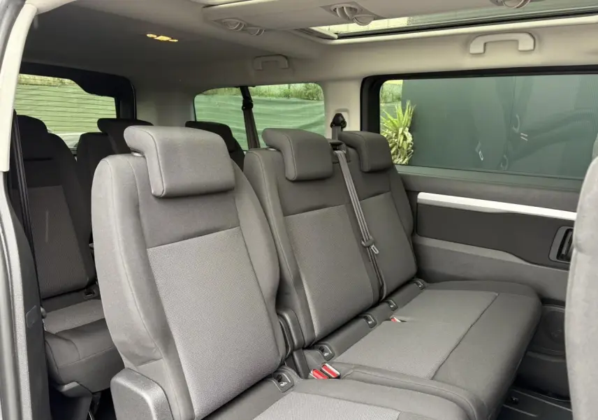 Vue intérieure côté droit des sièges arrière gris du Opel Zafira Life XL avec toit panoramique visible au plafond