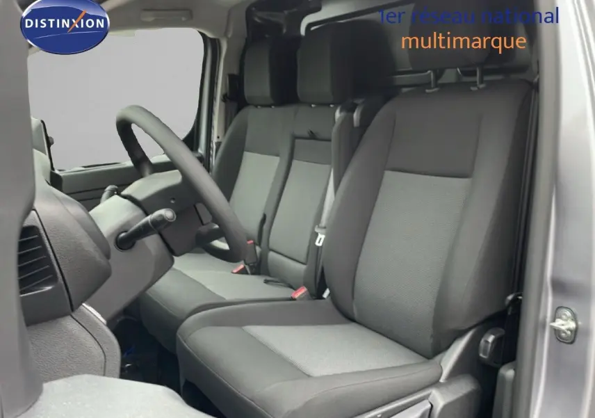 Vue intérieure côté conducteur du Citroën Jumpy gris Artense, montrant les sièges tissu gris et noir et le volant multifonction.