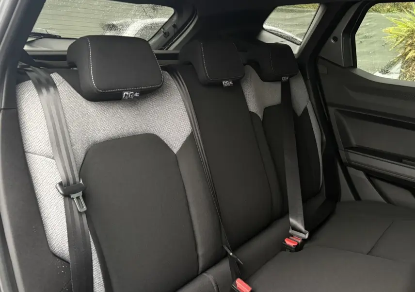 Vue intérieure des sièges arrière du Dacia Duster 2026, tissu bicolore gris et noir avec ceintures de sécurité visibles.