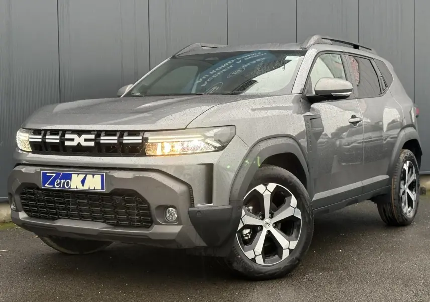 SUV Dacia Duster gris schiste en 3/4 avant droit, avec jantes alliage et signature lumineuse LED allumée.