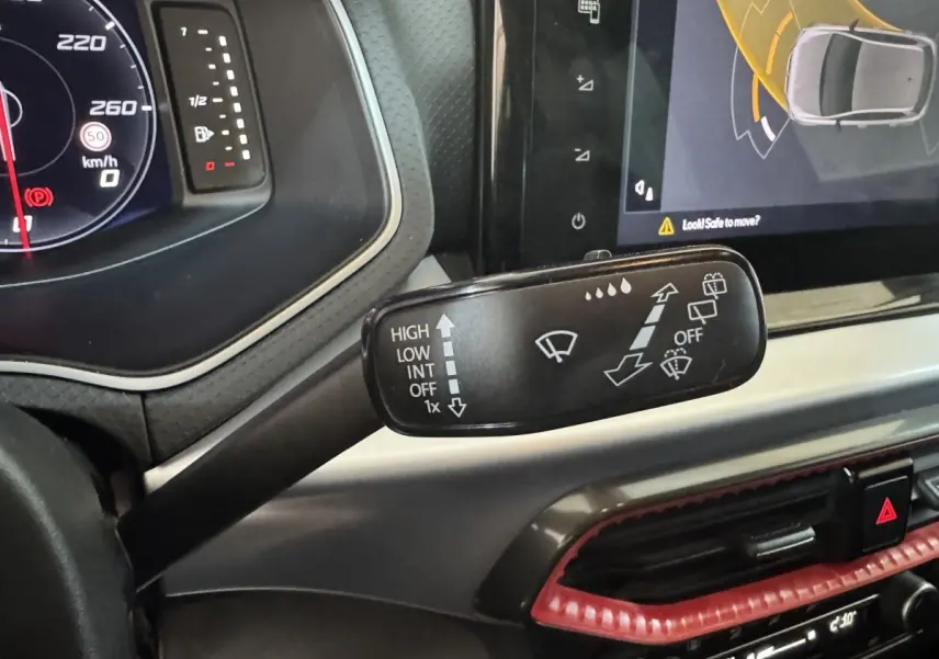 Gros plan sur la commande des essuie-glaces à gauche du volant dans l’habitacle rouge et noir d’une SEAT Ibiza 2024.