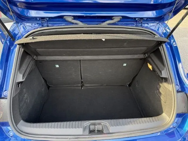 Coffre ouvert vu de dessus d'une Renault Clio V bleu Iron, montrant l'espace de chargement vide et la garniture noire intérieure.