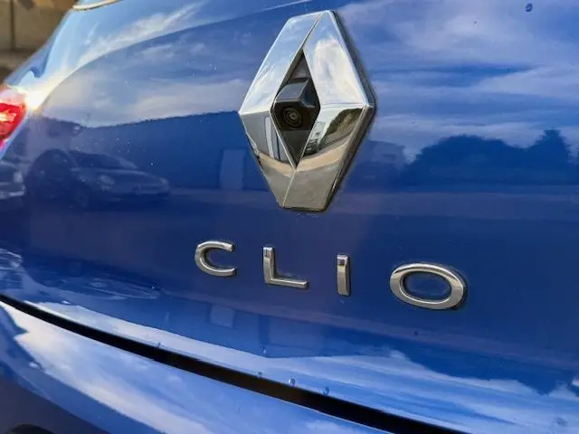 Gros plan sur le logo Renault et l’inscription Clio sur la malle arrière d’une Renault Clio V bleu Iron.