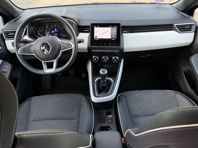 Vue intérieure avant de la Renault Clio V 1.3 TCE 140 Intens 2022, tableau de bord noir et gris avec écran tactile central et boîte manuelle.