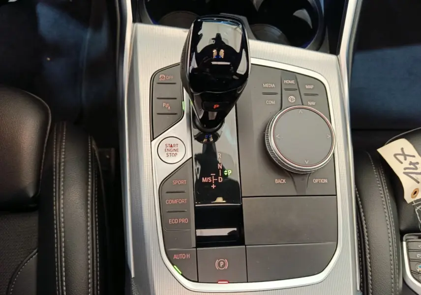Vue rapprochée de la console centrale BMW Série 3 318d 2022 avec levier de vitesse noir et boutons de mode de conduite.