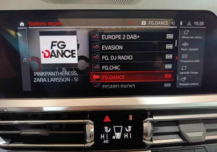 Écran tactile central de la BMW Série 3 318d 2022 affichant les stations radio DAB, avec commandes climatisation en dessous.