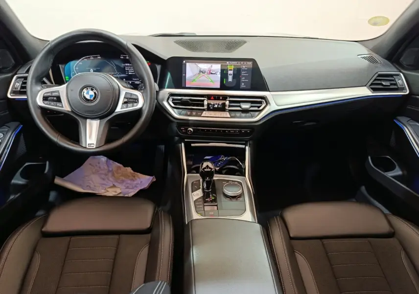Intérieur BMW Série 3 318d 2022 vu de face, tableau de bord noir avec écran tactile central et volant cuir multifonctions.