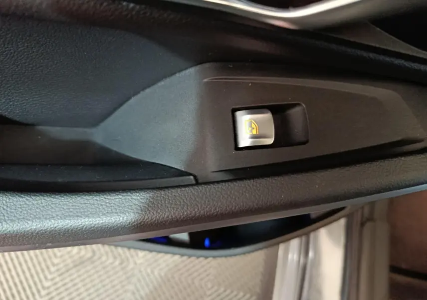 Gros plan sur le bouton de commande de lève-vitre côté conducteur dans l’habitacle noir d’une BMW Série 3 gris clair 2022.
