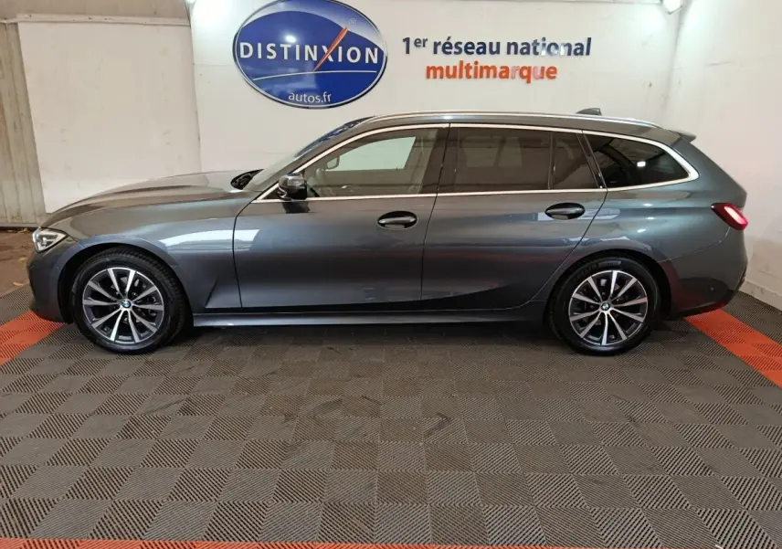 Vue de profil côté gauche d'une BMW Série 3 Touring gris clair avec jantes alliage et rails de toit noirs.