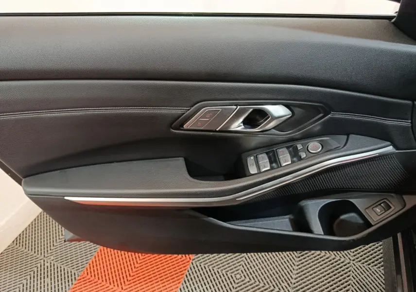 Gros plan sur la porte intérieure côté gauche de la BMW Série 3 318d 2022, avec commandes de vitres et poignée argentée.