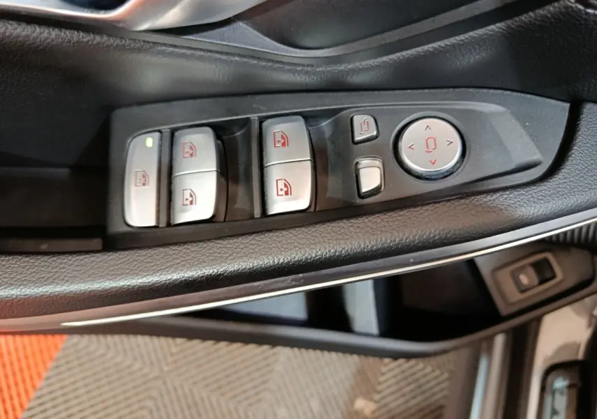 Gros plan sur les commandes des vitres et rétroviseurs côté conducteur d’une BMW Série 3 gris clair 318d Lounge 2022.