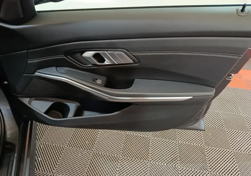 Vue intérieure du panneau de porte côté gauche gris foncé avec poignée argentée et insert décoratif sur BMW Série 3 318d 2022.