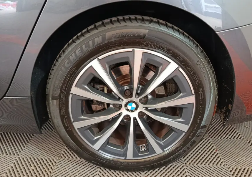 Gros plan sur la roue avant droite d'une BMW Série 3 gris clair, jante alliage à multiples branches.