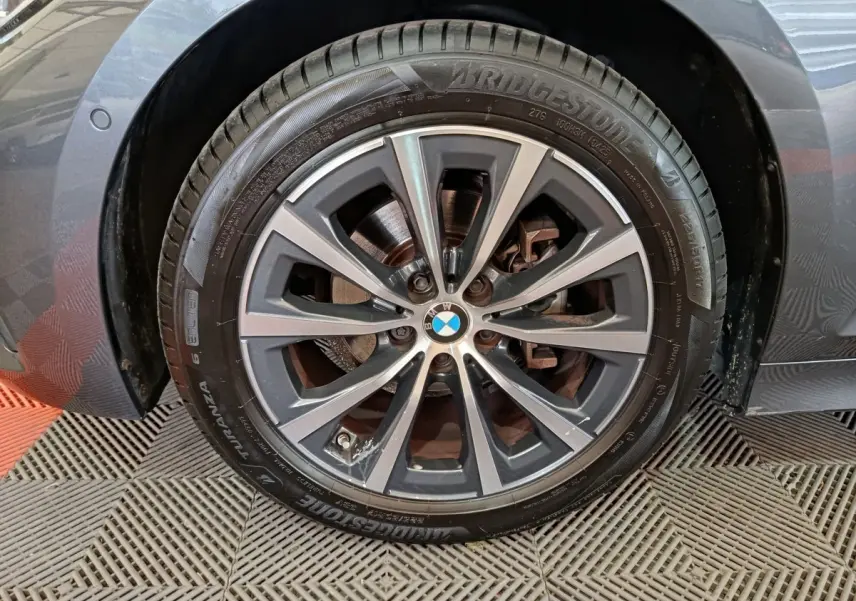 Gros plan sur la roue avant gauche grise d’une BMW Série 3 318d avec jante alliage et pneu Bridgestone.