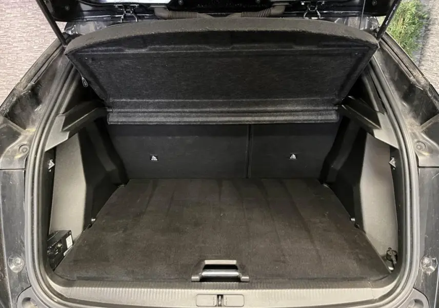 Coffre ouvert vu de l'arrière d'un Peugeot 2008 noir, montrant l'espace de chargement et la tablette cache-bagages relevée.