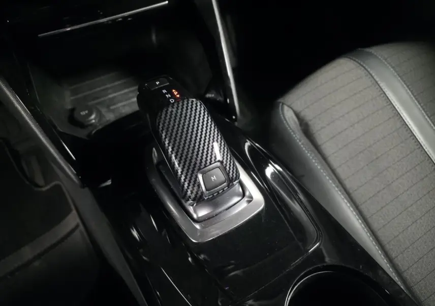 Le levier de vitesse automatique noir à effet carbone de la Peugeot 2008 1.5 BlueHDi, avec siège tissu gris à côté.
