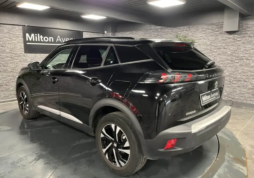 Peugeot 2008 noir perla nacré vue 3/4 arrière droit en intérieur, jantes alliage bi-ton et feux arrière LED griffés.