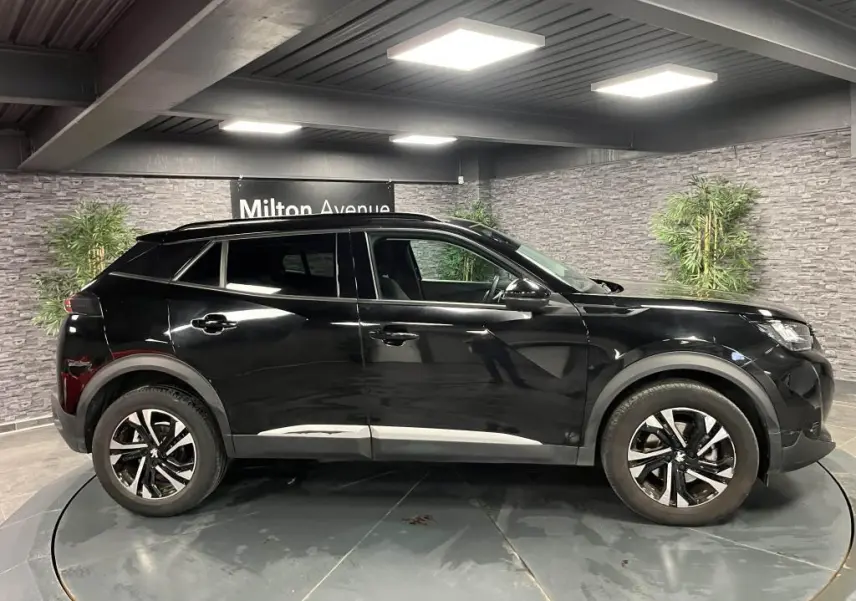 Peugeot 2008 noir perla nacré vue de profil côté gauche, jantes alliage bi-ton et barres de toit noires.
