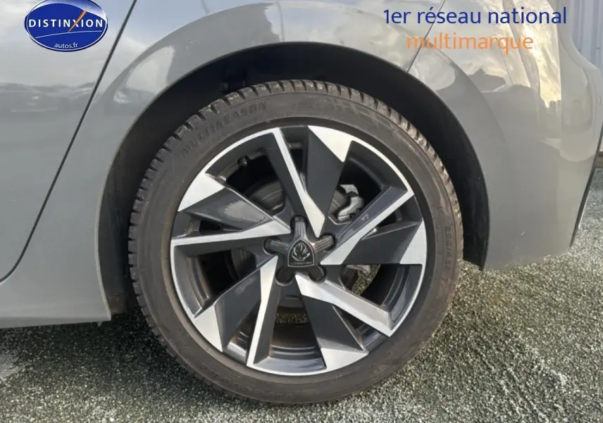 Gros plan sur la roue arrière droite d'une Peugeot 308 gris sélénite avec jante alu au design moderne.