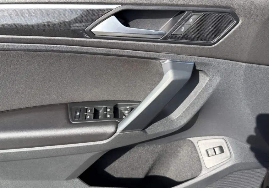 Vue rapprochée de la porte avant gauche noire du Volkswagen Tiguan 2022 avec commandes de vitres et verrouillage.