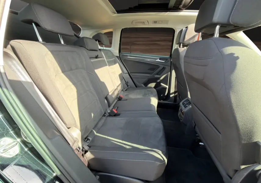 Vue intérieure arrière du Volkswagen Tiguan 2022 noir, sièges en tissu gris et toit ouvrant panoramique visible.