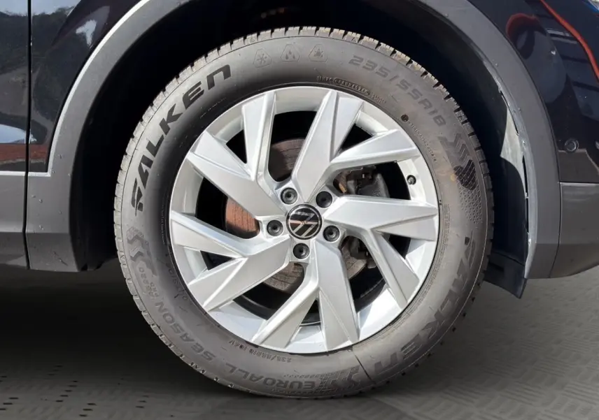 Gros plan sur la roue avant gauche du Volkswagen Tiguan noir, jante alliage argentée avec logo VW central.