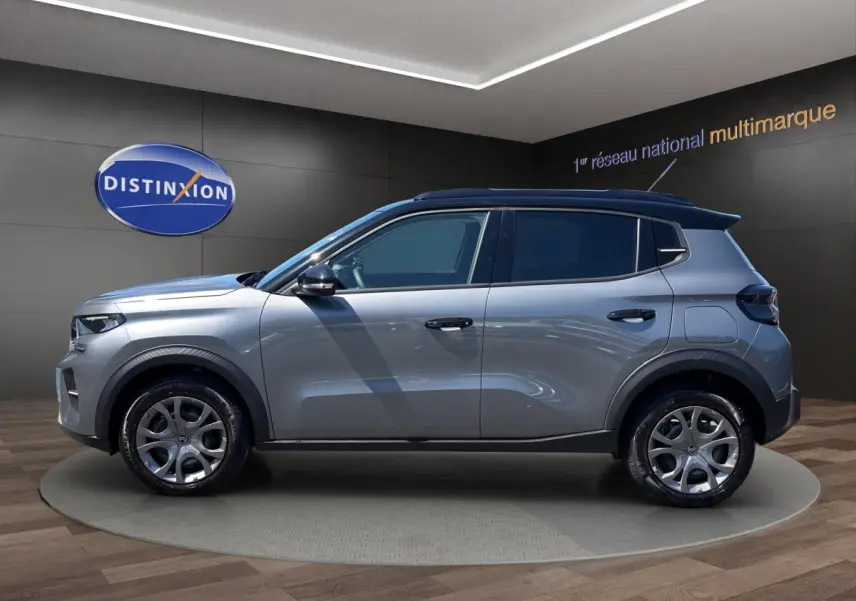 Profil droit d'une Citroën C3 2025 gris foncé avec toit noir et jantes alliage en showroom.