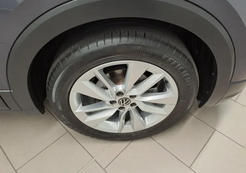 Gros plan sur la roue avant droite du Volkswagen T-Cross gris cendré avec jante alliage à 5 doubles branches.