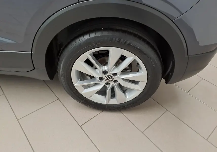 Gros plan sur la roue arrière droite du Volkswagen T-Cross gris cendré avec jante alliage à 5 doubles branches.