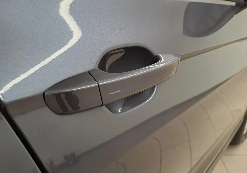Poignée de porte côté gauche du Volkswagen T-Cross 2025 en gris cendré métallisé avec finition lisse et moderne.