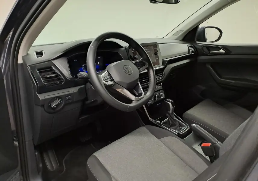 Vue intérieure côté conducteur du Volkswagen T-Cross 2025, tableau de bord moderne avec volant multifonction et sellerie grise.
