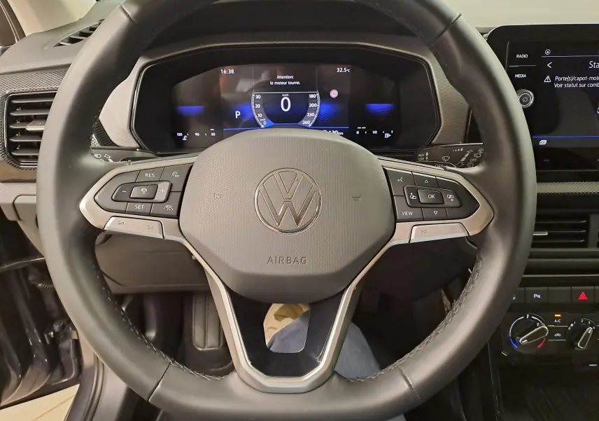 Vue rapprochée du volant noir et gris du Volkswagen T-Cross 2025 avec tableau de bord digital et commandes intégrées.