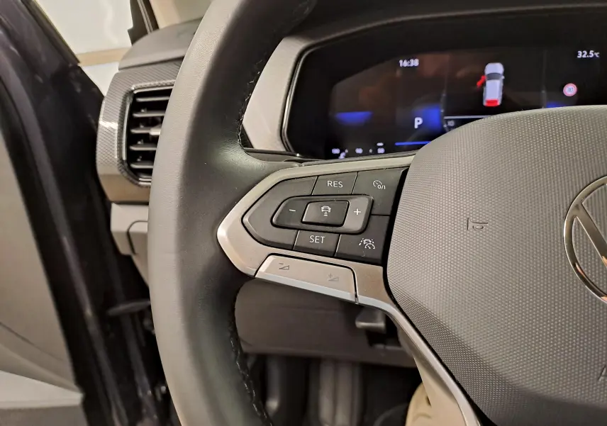 Gros plan sur la partie gauche du volant noir du Volkswagen T-Cross 2025 avec commandes intégrées et tableau de bord numérique.