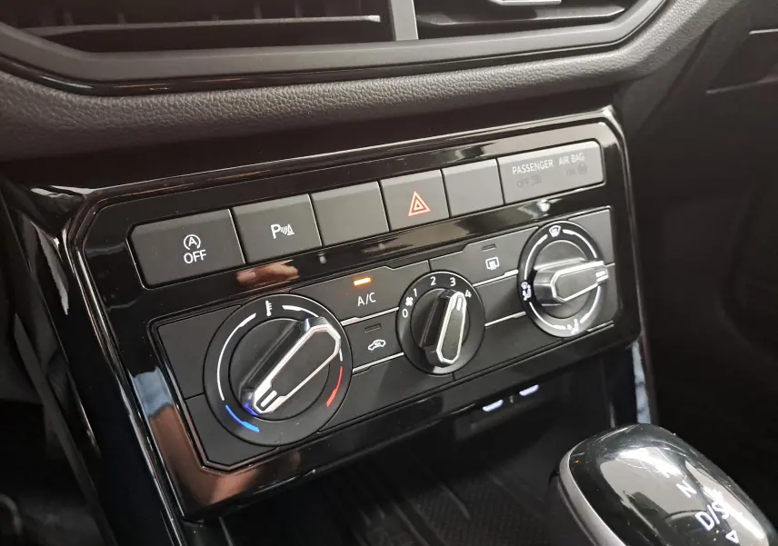 Gros plan sur la console centrale du Volkswagen T-Cross 2025 avec commandes de climatisation et levier de vitesse.