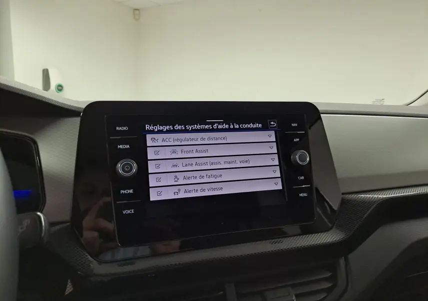 Vue intérieure du tableau de bord du Volkswagen T-Cross 2025, écran tactile affichant les réglages d'aide à la conduite.