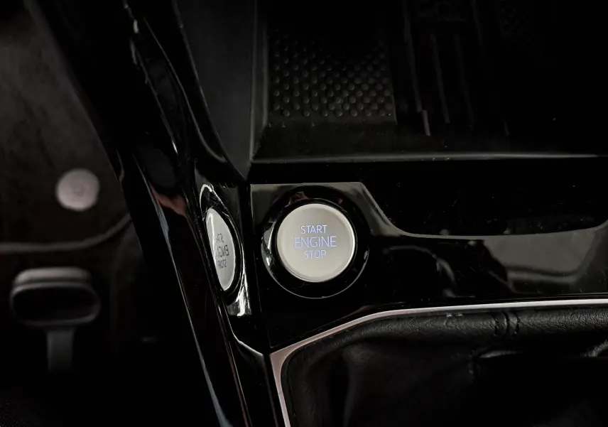 Bouton Start Engine Stop en gros plan sur la console centrale noire d'un Volkswagen T-Cross gris cendré 2025.