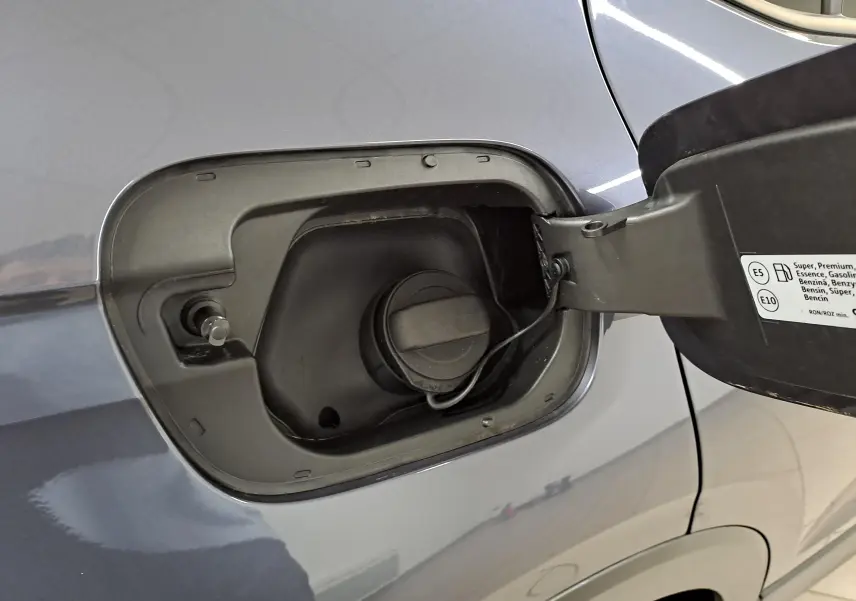 Gros plan sur la trappe à carburant ouverte du Volkswagen T-Cross gris cendré, montrant le bouchon essence fixé.
