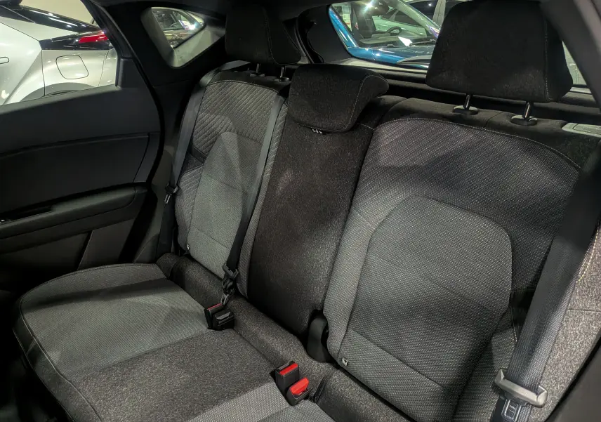 Vue intérieure sur les sièges arrière en tissu gris du Renault Captur 2025, avec ceintures de sécurité et appuie-têtes visibles.