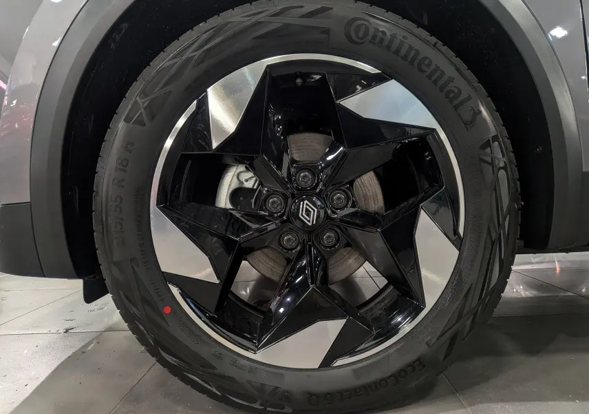 Gros plan sur la roue avant gauche du Renault Captur gris Cassiopé, avec jante noire et argentée au design étoilé.