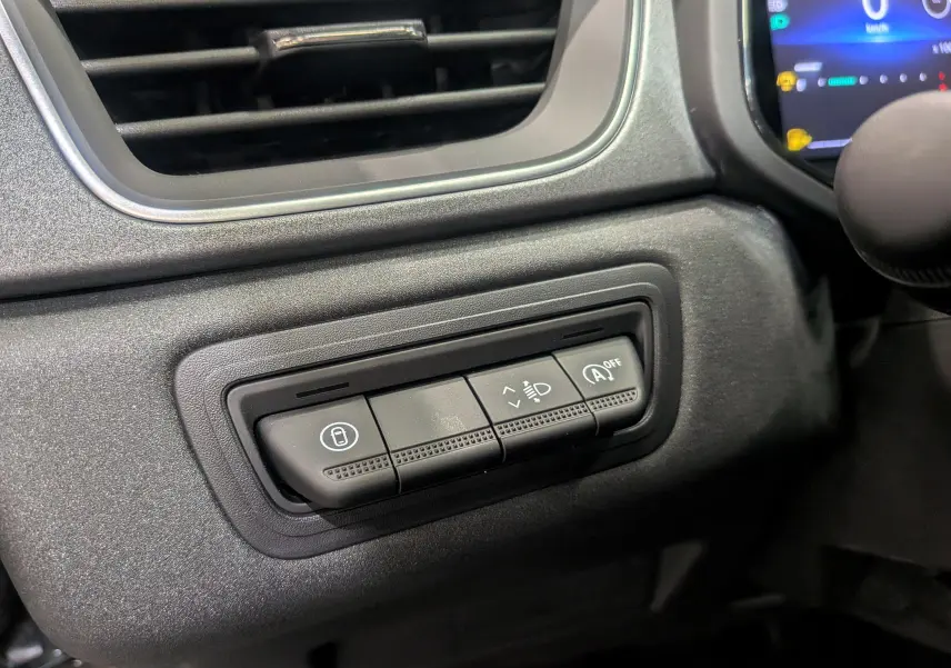 Gros plan sur les commandes situées à gauche du volant du Renault Captur gris Cassiopé 2025, avec réglage phares et arrêt auto start-stop.