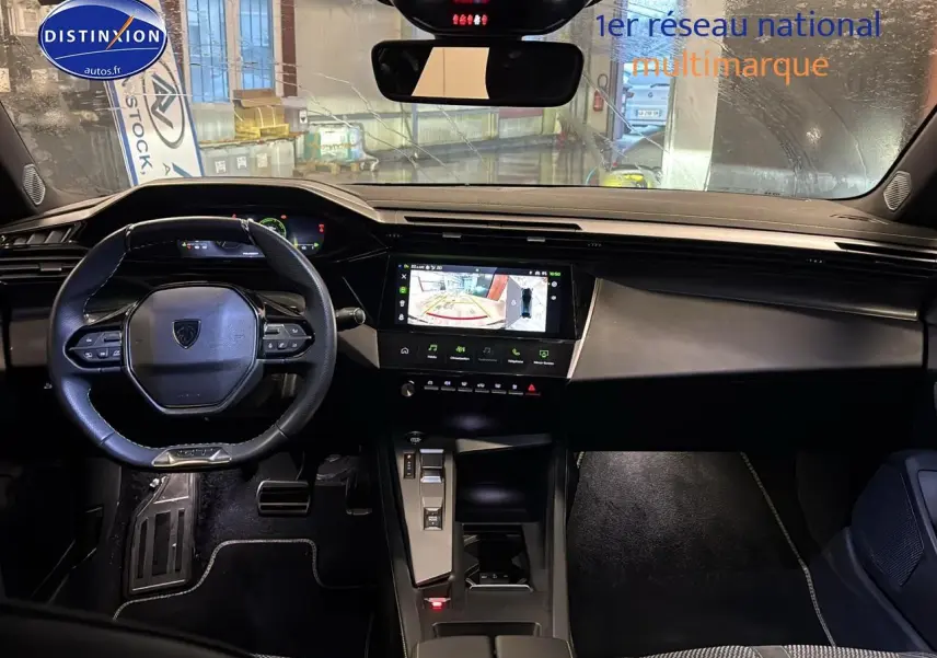 Vue intérieure avant de la Peugeot 408 Hybrid gris sellenium, avec tableau de bord numérique et écran tactile affichant la caméra de recul.