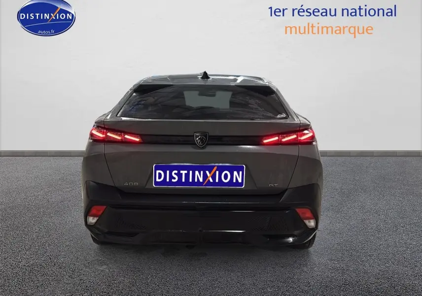Vue arrière d'une Peugeot 408 Hybrid gris sellenium avec feux LED allumés et logo central visible.