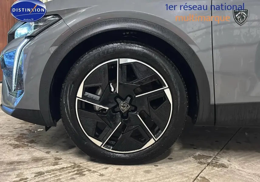 Gros plan sur la roue avant gauche et partie avant grise sélénite d'une Peugeot 408 Hybrid 145 GT e-dcs6 2025.
