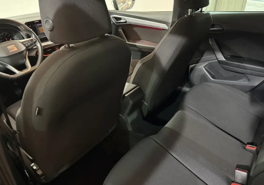 Vue intérieure arrière de la SEAT IBIZA 1.0 TSI 110 FR 2024, sièges tissu noirs et tableau de bord partiel visible.