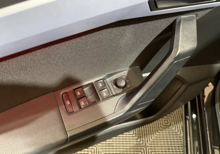 Gros plan sur la commande des vitres et rétroviseurs côté conducteur de la SEAT Ibiza noire 2024.