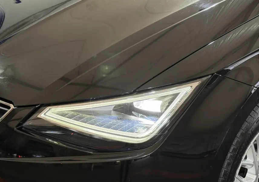 Gros plan sur le phare avant droit LED d’une SEAT Ibiza 1.0 TSI 110 FR noire, avec carrosserie brillante.