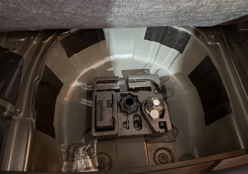 Vue plongeante sur le coffre ouvert d'une SEAT Ibiza noire, montrant le rangement sous la tablette sans roue de secours.