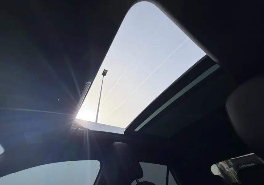 Vue intérieure du toit ouvrant panoramique ouvert du Volkswagen T-Roc blanc pur avec ciel de pavillon noir.