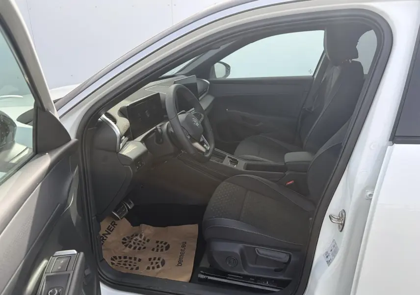 Vue intérieure côté gauche du Volkswagen T-Roc blanc pur, montrant les sièges sport noirs et le tableau de bord moderne.