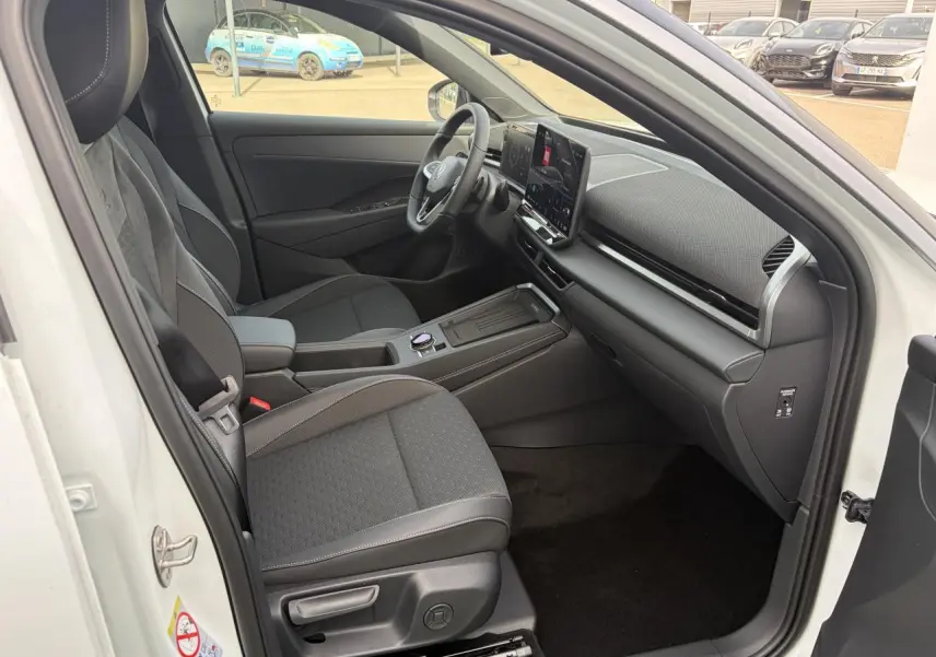 Intérieur avant droit du Volkswagen T-Roc blanc pur, avec tableau de bord moderne et sièges tissu R-Line noirs.